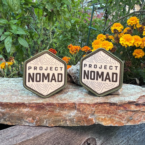 Two Project NOMAD woven patches on a stone ledge